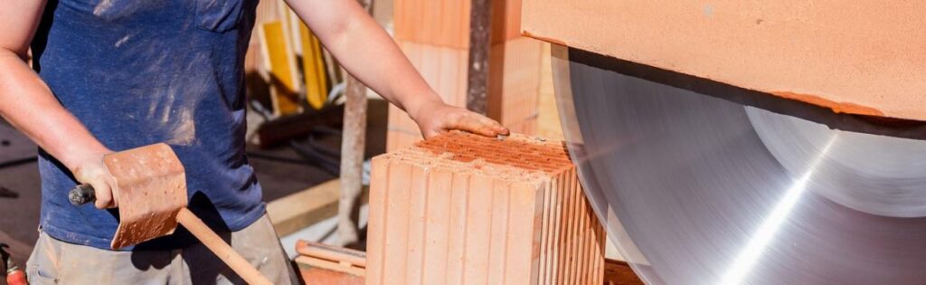 Die Qualität der handwerklichen Arbeit entscheidet 1 Das Bild zeigt einen Maurer bei dem Zuschnitt eines Ziegelsteins mit Porung.