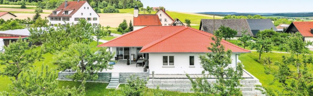 Auf dem Bild ist ein Bungalow mit Ziegelroten Dachziegeln zu sehen.